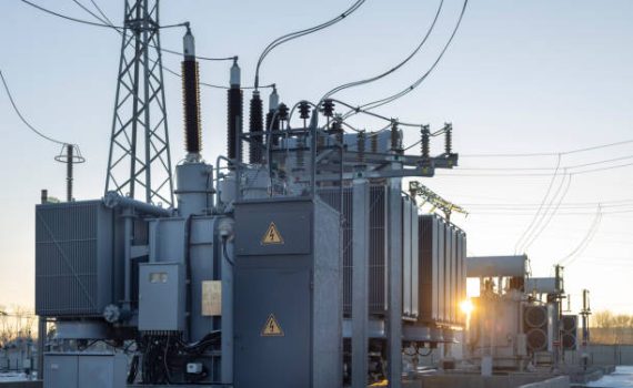 High-voltage transformer substation in winter at dawn. High voltage equipment. Energy transfer technology.
