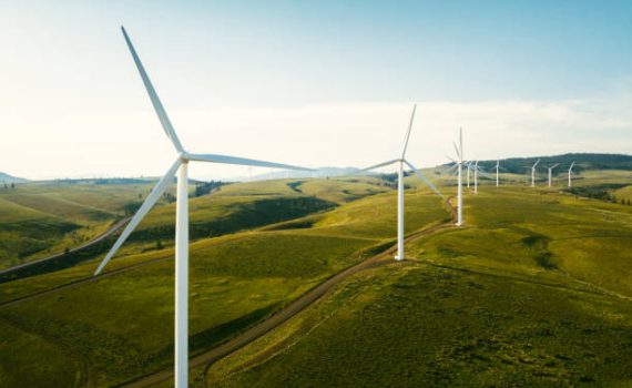 Wind turbines tower above the earth in a rural setting, drawing renewable energy as they spin. Sustainable energy and green technology that considers the environment.   Shot in Washington state, USA.