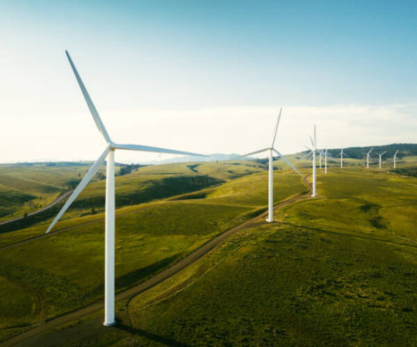 Wind turbines tower above the earth in a rural setting, drawing renewable energy as they spin. Sustainable energy and green technology that considers the environment.   Shot in Washington state, USA.